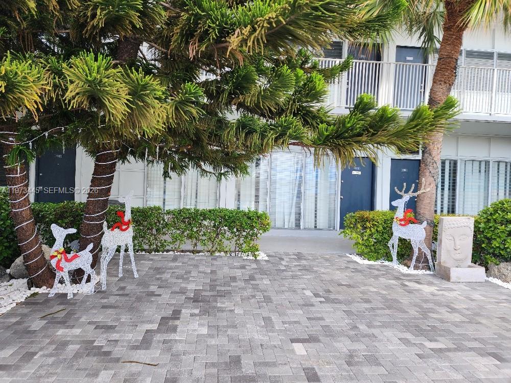 A paved courtyard features a large pine tree, decorative reindeer figures, and a building exterior — 2101 Normandy Dr # 310, Miami Beach FL 33141, MIAMI BEACH, FL