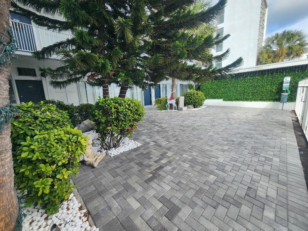 A paved courtyard features manicured shrubs, white landscaping stones, and a large evergreen tree — 2101 Normandy Dr # 310, Miami Beach FL 33141, MIAMI BEACH, FL