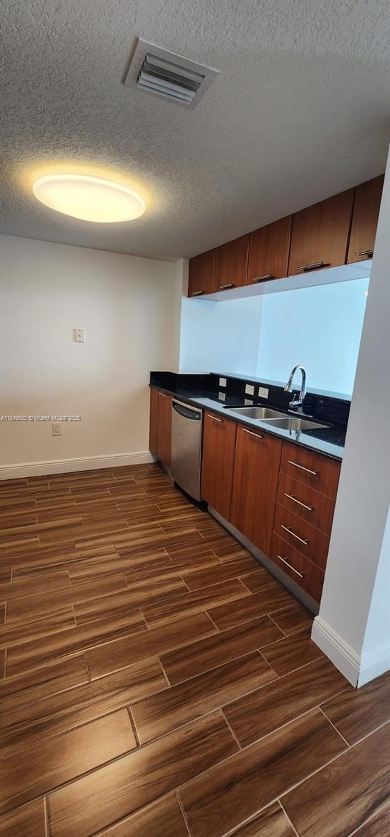 A kitchen features wood-toned cabinets, black countertops, stainless steel appliances, and wood-look tile flooring — 1800 N Bayshore Dr # 3808, Miami FL 33132, MIAMI, FL