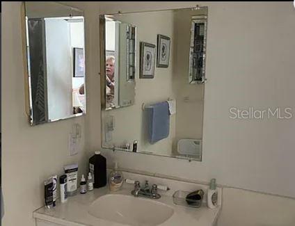 A bathroom vanity features a white countertop, a sink, and two wall-mounted mirrors — 293 DORSET G UNIT G, BOCA RATON, FL