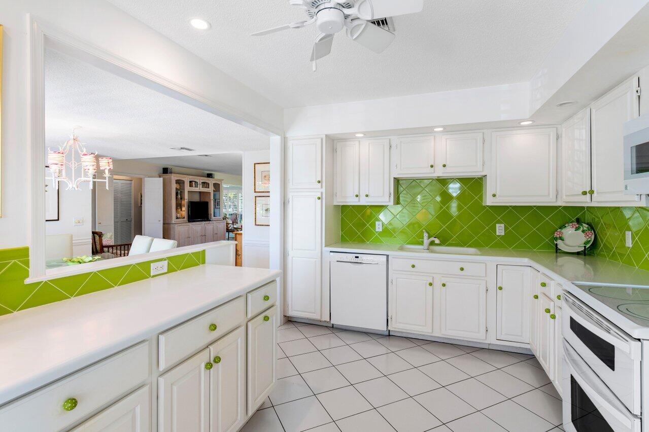 A kitchen with white cabinets, a bright green tiled backsplash, and white tile flooring — 3870 Quail Ridge Drive, Boynton Beach FL 33436, BOYNTON BEACH, FL