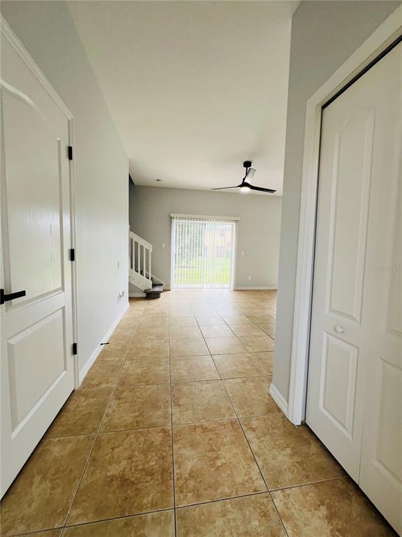 A tiled hallway leads to an open living area with stairs and sliding glass doors — 9096 IRON OAK AVENUE, TAMPA, FL