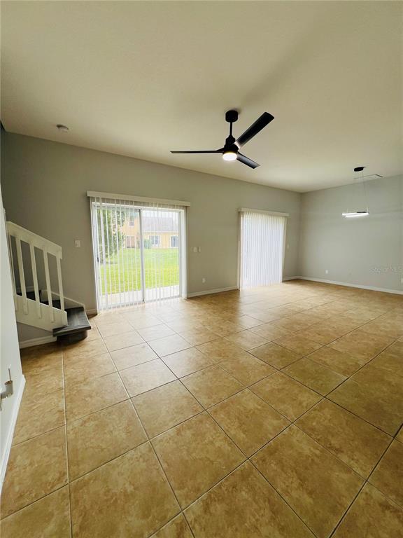 An open living area features tile flooring, a ceiling fan, and sliding glass doors — 9096 IRON OAK AVENUE, TAMPA, FL