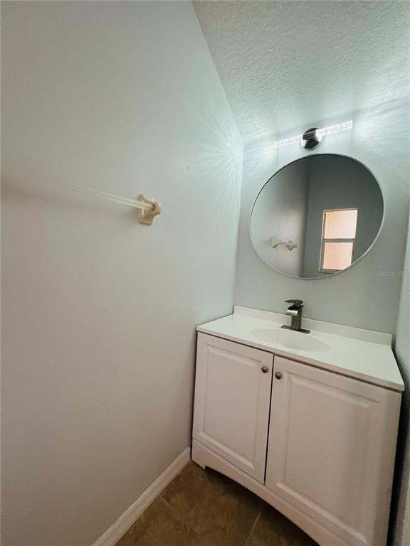 A bathroom vanity with a white cabinet, sink, and round mirror against a light wall — 9096 IRON OAK AVENUE, TAMPA, FL