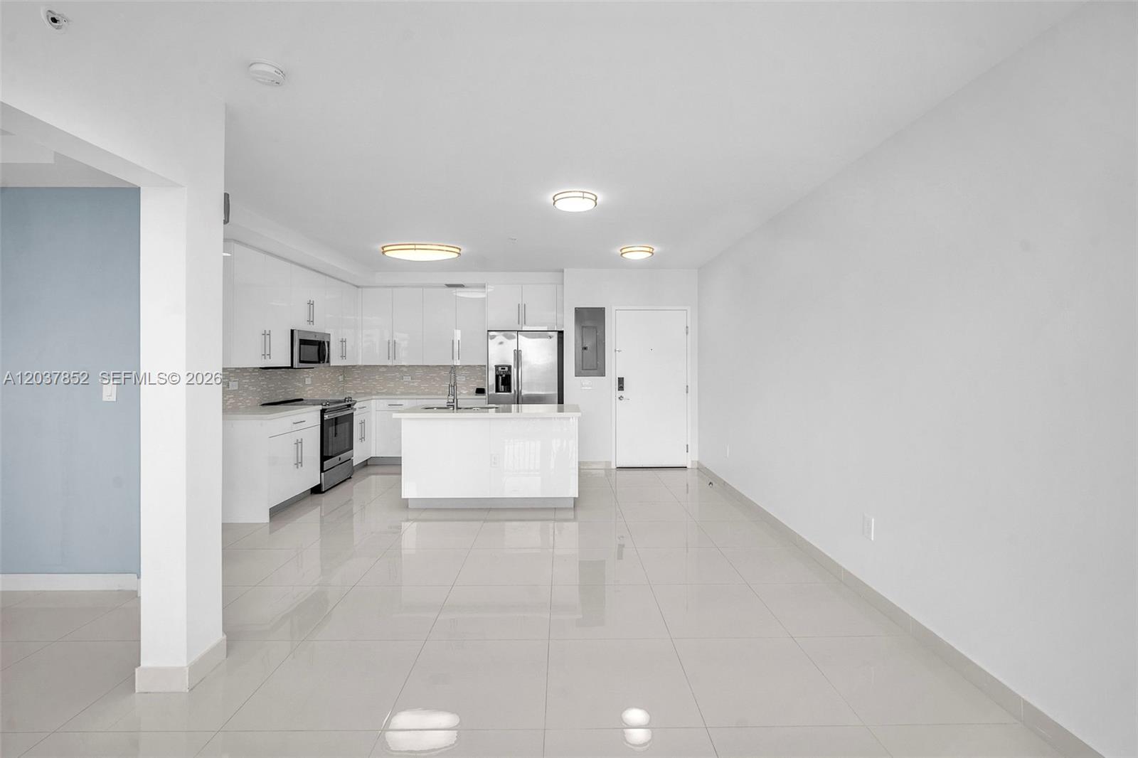 A modern kitchen features white cabinetry, stainless steel appliances, and a central island — 2651 NE 212th Ter # 301, Miami FL 33180, MIAMI, FL