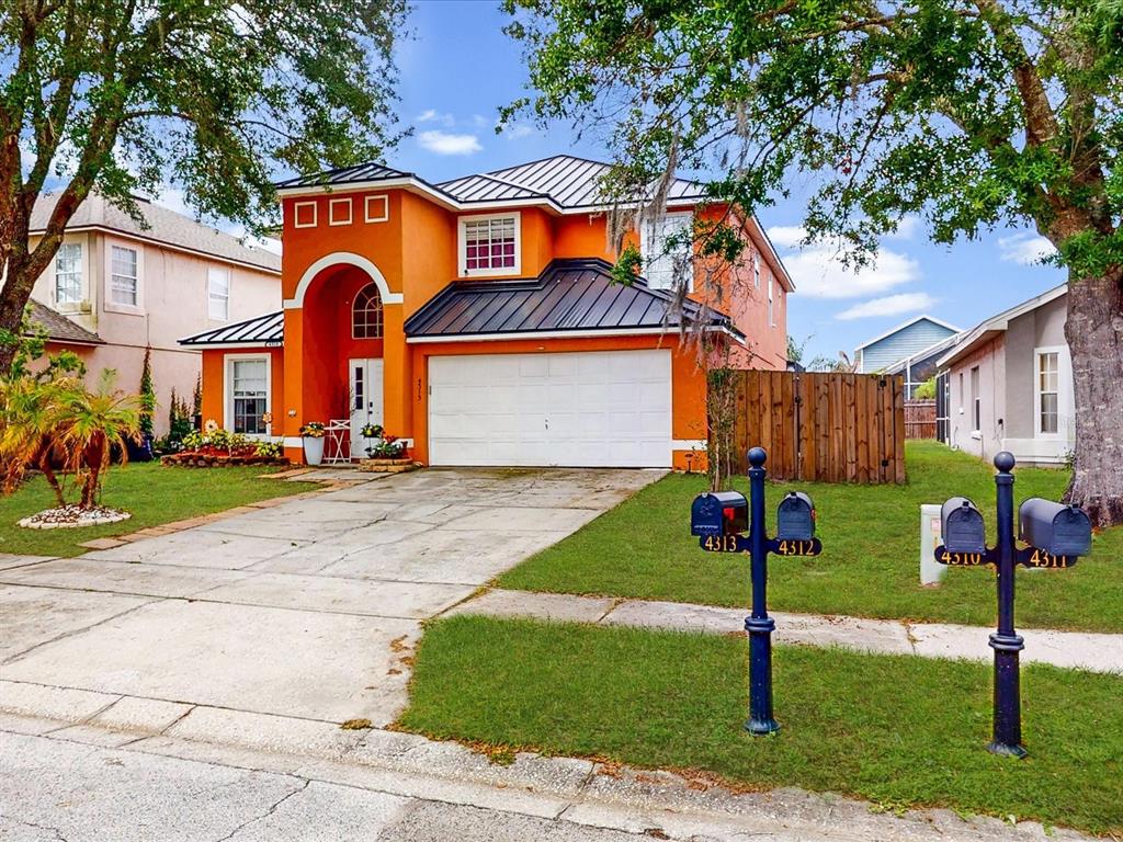 A two-story orange house with a metal roof and a two-car garage — 4313 BAY BROOK DRIVE, KISSIMMEE, FL