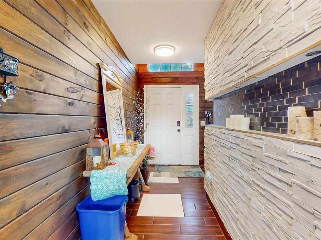 An entryway features wood-paneled walls, a stone accent wall, and a console table with decor — 4313 BAY BROOK DRIVE, KISSIMMEE, FL