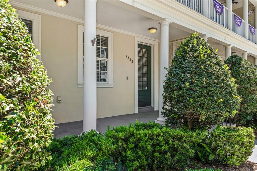 A covered porch features a dark green front door, white columns, and manicured landscaping — 1353 CHATFIELD PLACE, ORLANDO, FL