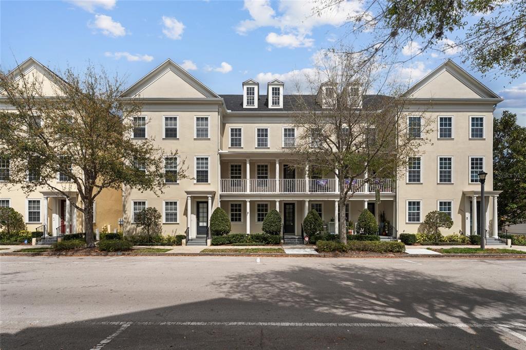 A row of three-story townhomes with balconies, columns, and gabled roofs under a blue sky — 1353 CHATFIELD PLACE, ORLANDO, FL