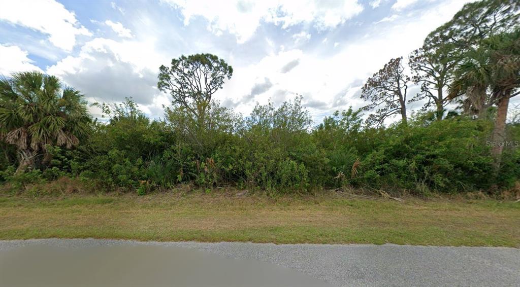 A view of a vacant, heavily wooded lot from a paved road — 13177 WINDCREST DRIVE, PORT CHARLOTTE, FL