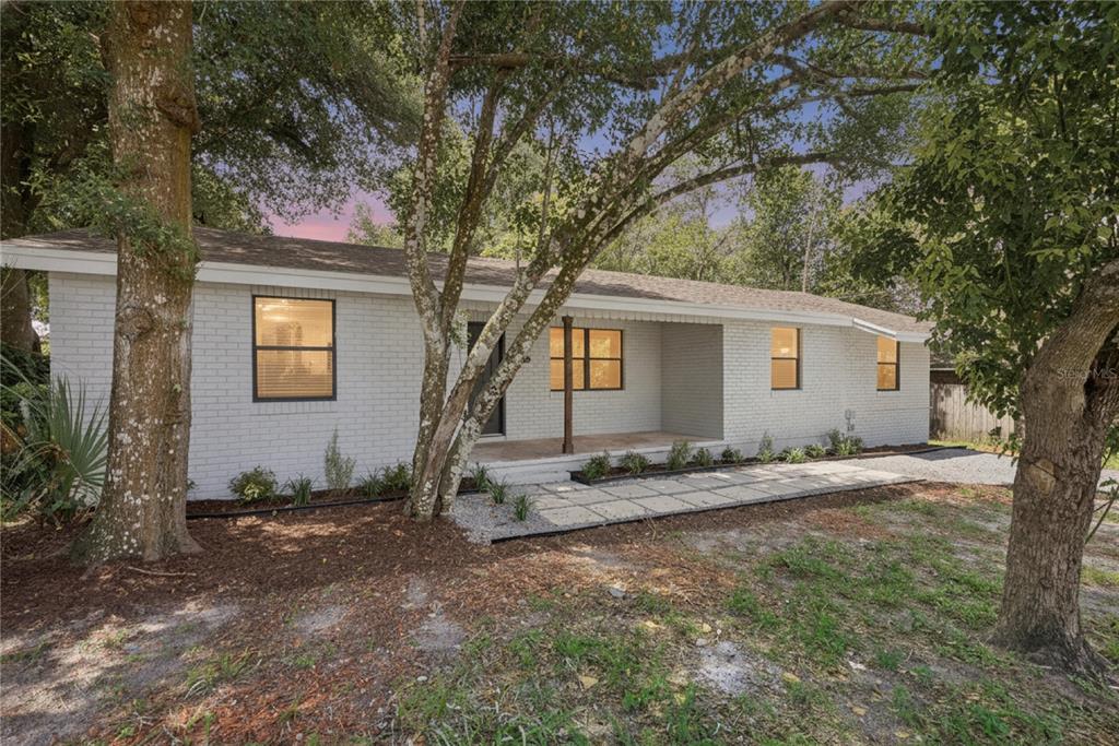 A single-story white brick house features a covered front porch and a stone walkway — 137 LUCERNE DRIVE, DEBARY, FL