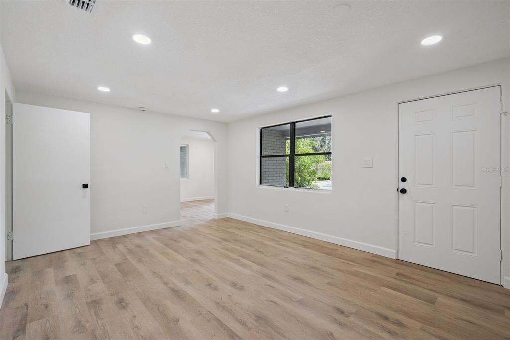 An empty room with white walls, recessed lighting, wood-look flooring, and a white entry door — 137 LUCERNE DRIVE, DEBARY, FL