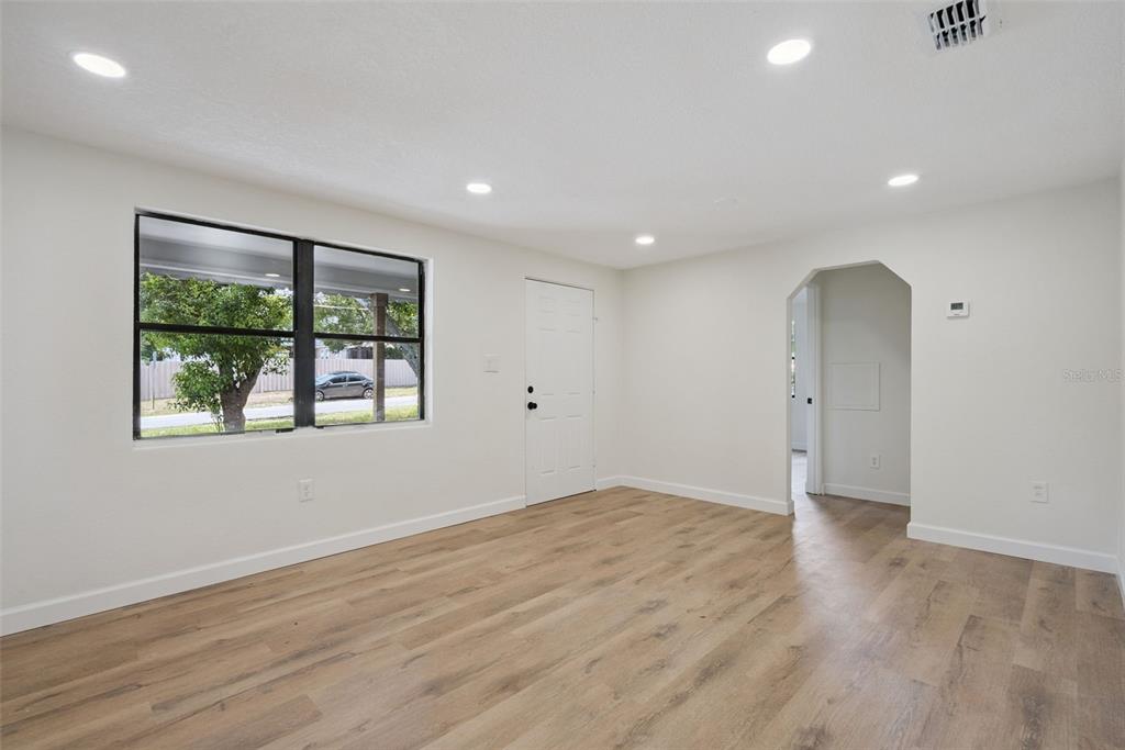 A bright, empty room features white walls, recessed lighting, and light wood-look flooring — 137 LUCERNE DRIVE, DEBARY, FL
