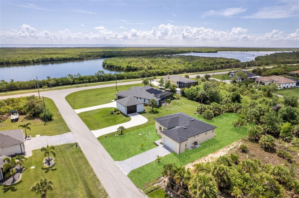 An aerial view shows two suburban houses surrounded by green lawns and coastal vegetation — 15419 SEAFOAM CIRCLE, PORT CHARLOTTE, FL
