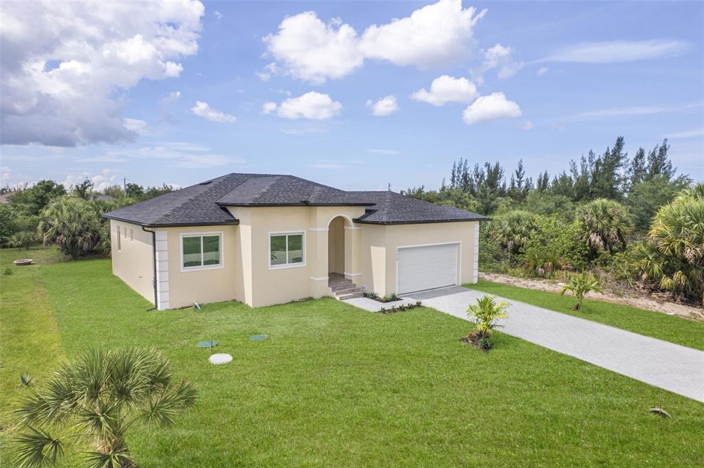 A single-story house with a beige stucco exterior, dark roof, and attached garage — 15419 SEAFOAM CIRCLE, PORT CHARLOTTE, FL
