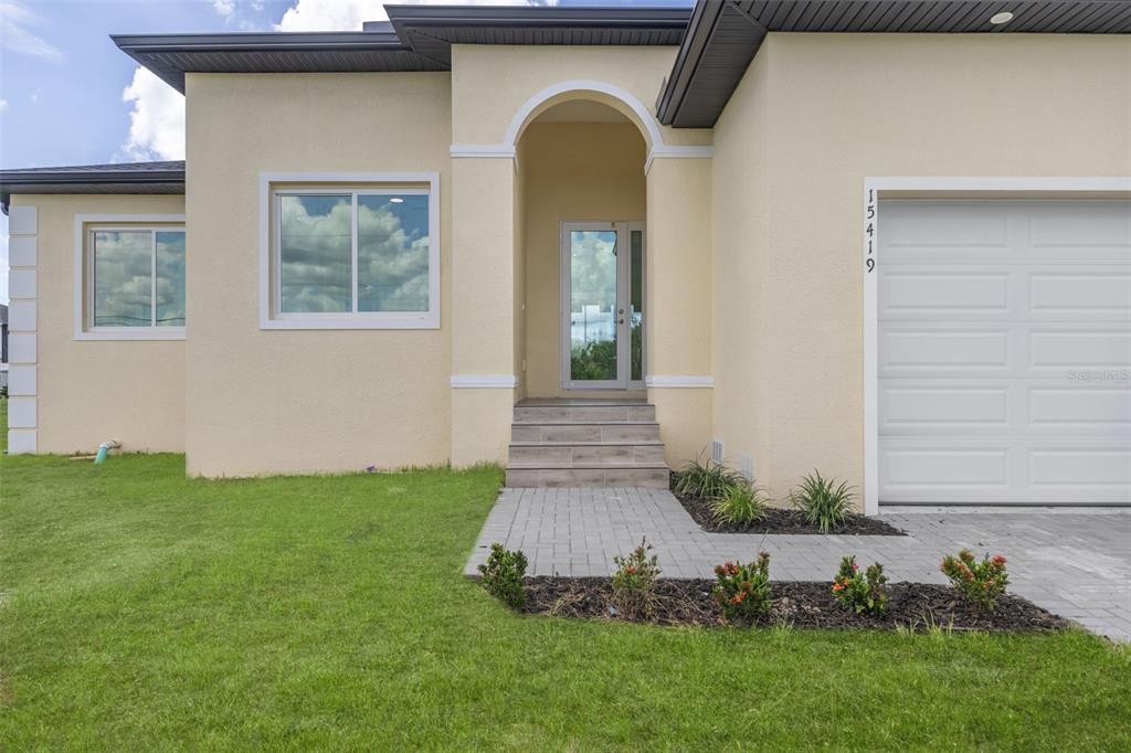The exterior of a beige single-story house features a paved walkway, front steps, and garage — 15419 SEAFOAM CIRCLE, PORT CHARLOTTE, FL