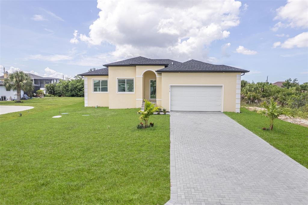 A single-story house with a beige stucco exterior, a gray shingled roof, and a paved driveway — 15419 SEAFOAM CIRCLE, PORT CHARLOTTE, FL