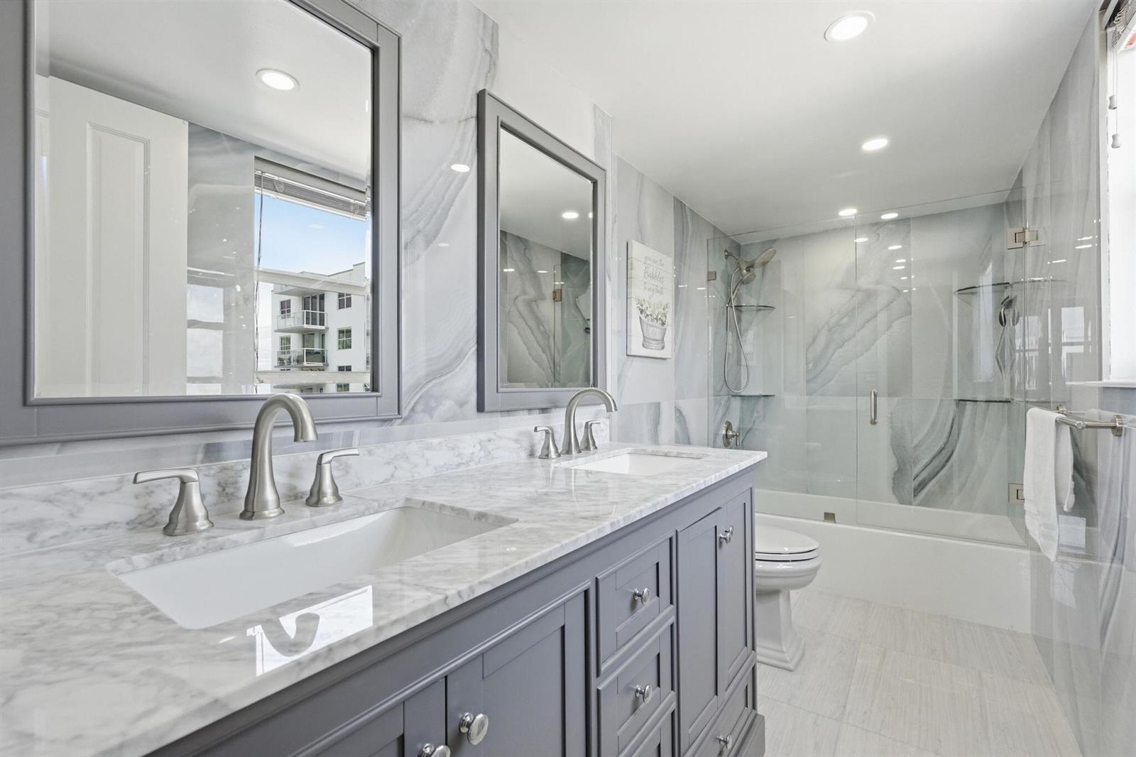 A modern bathroom features a double vanity with gray cabinets, marble countertops, and a shower — 3450 S Ocean Boulevard # 6010, Palm Beach FL 33480, PALM BEACH, FL