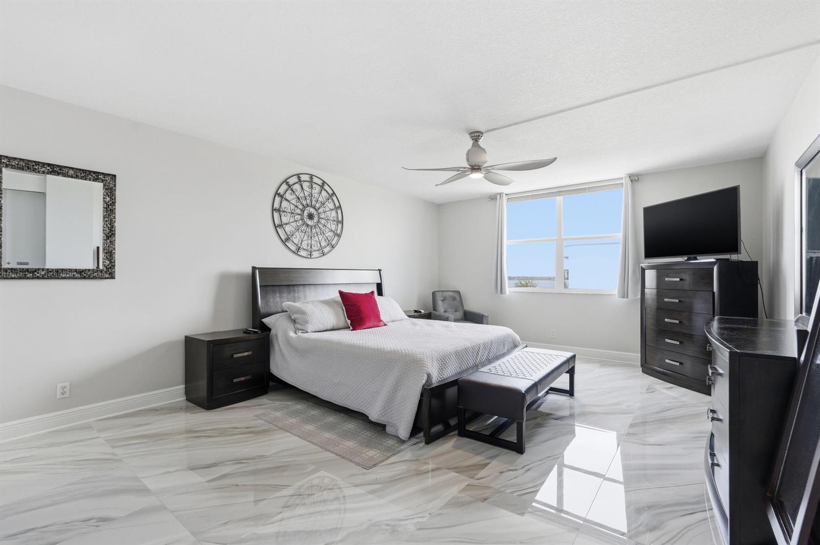 A bedroom features a dark wood bed frame, marble-look tile flooring, and a ceiling fan — 3450 S Ocean Boulevard # 6010, Palm Beach FL 33480, PALM BEACH, FL