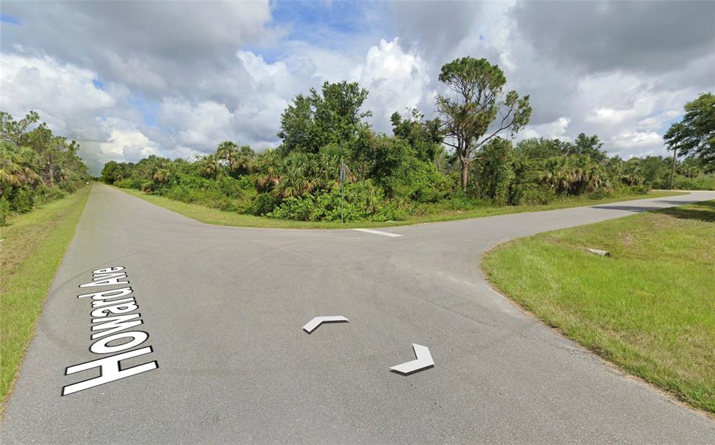 An asphalt road forks into two directions through a wooded, undeveloped area — 14272 HOWARD AVENUE, PORT CHARLOTTE, FL
