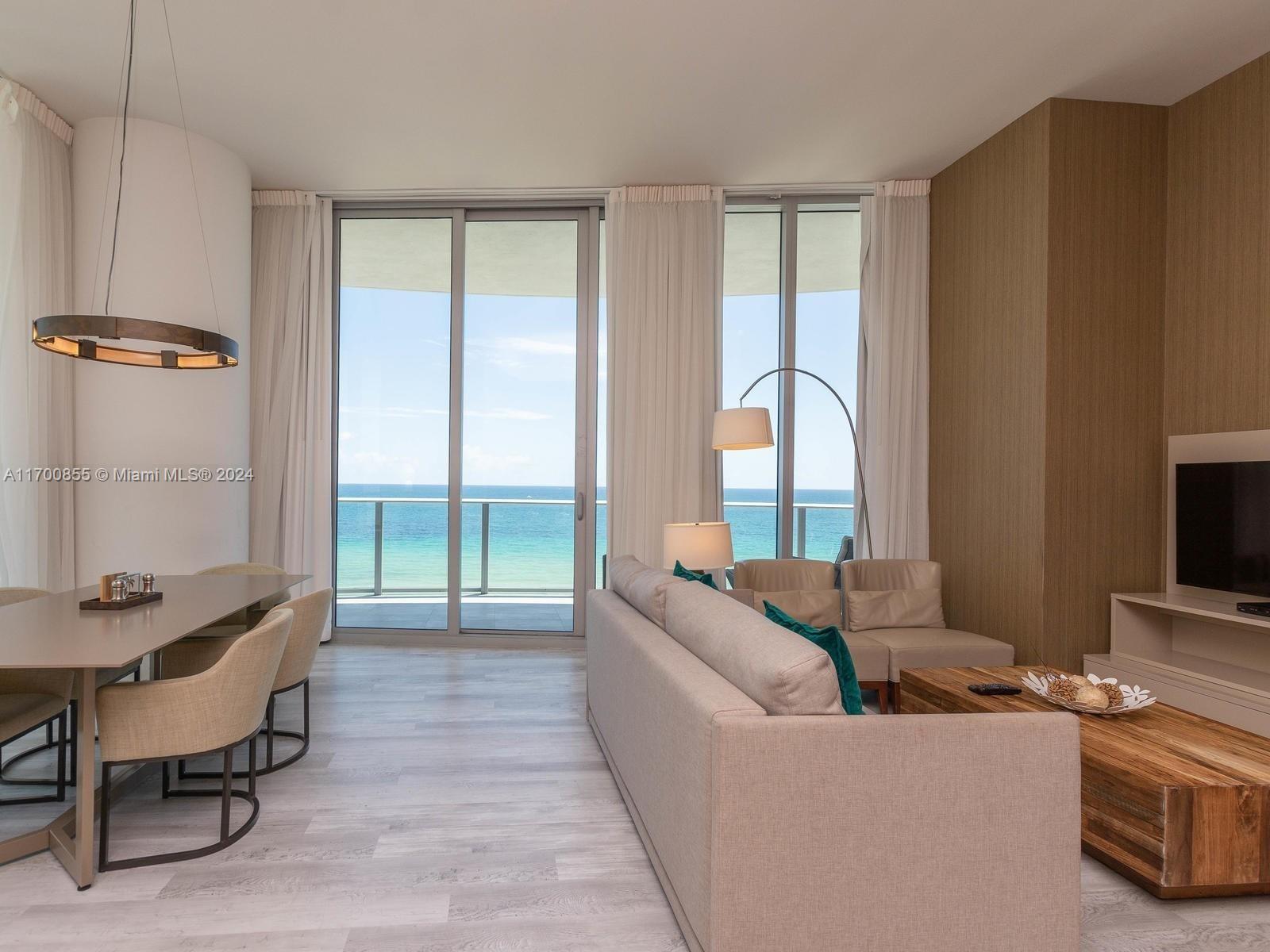 A modern living and dining area features floor-to-ceiling windows with a direct ocean view — 4111 S Ocean Dr # 601, Hollywood FL 33019, HOLLYWOOD, FL