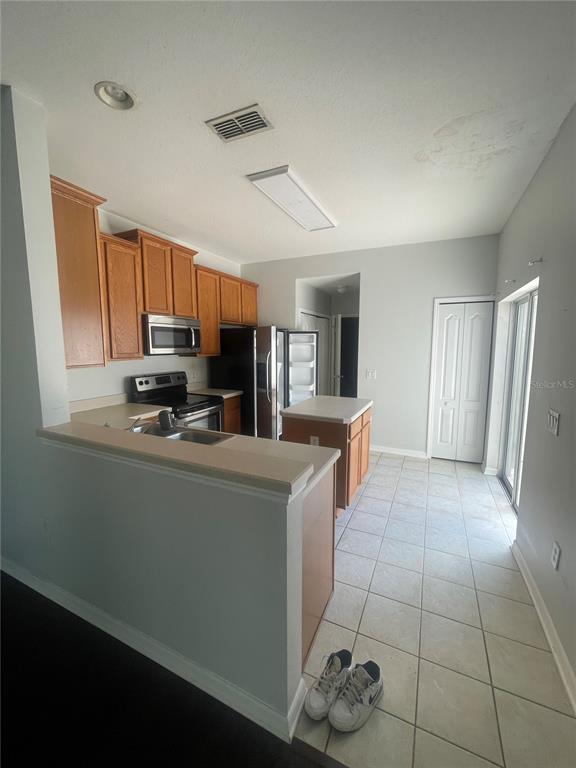 A kitchen with wood cabinets, stainless steel appliances, a center island, and tiled flooring — 14392 BRIDGEWATER CROSSINGS BOULEVARD, WINDERMERE, FL