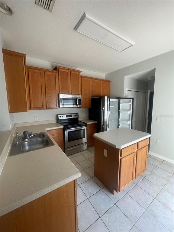 A kitchen features oak cabinets, stainless steel appliances, a center island, and tiled flooring — 14392 BRIDGEWATER CROSSINGS BOULEVARD, WINDERMERE, FL