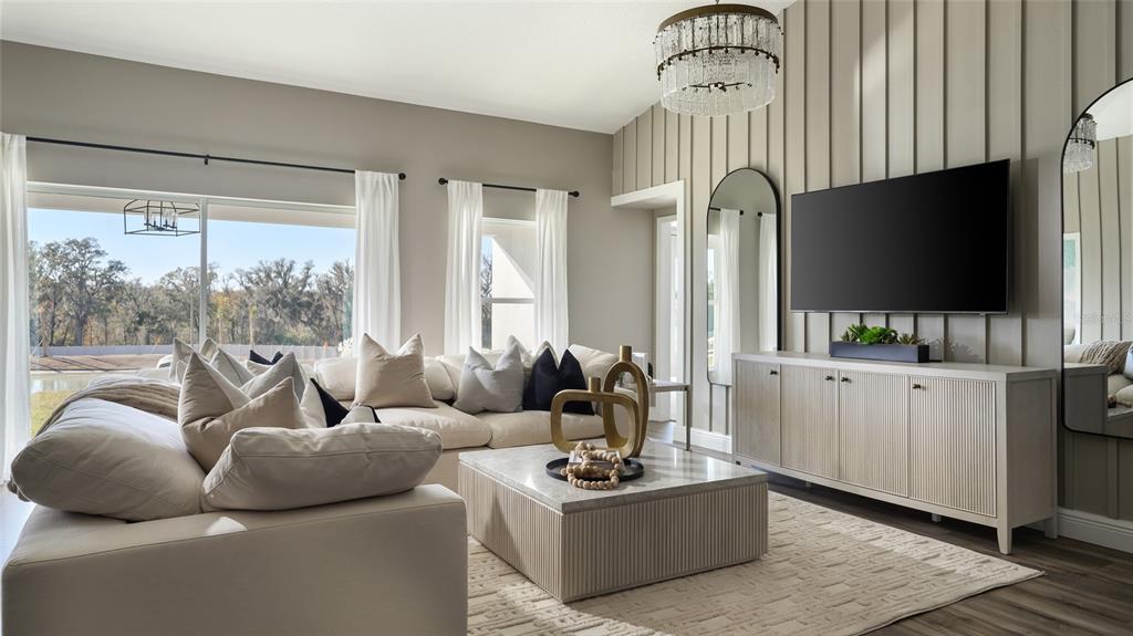A living room features a large sectional sofa, a coffee table, and a wall-mounted television — 9824 ANNUNCIATION DRIVE, WESLEY CHAPEL, FL