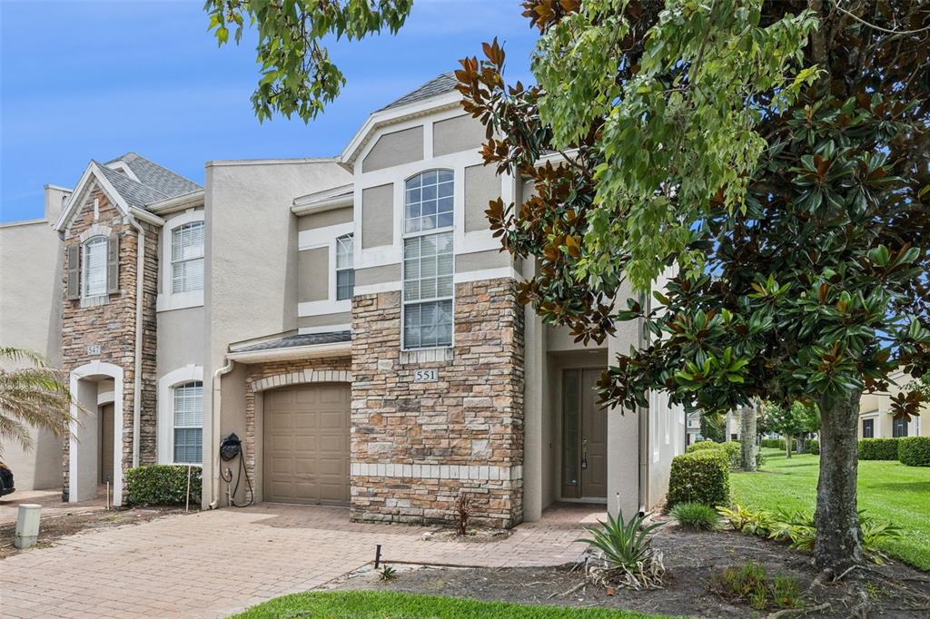 A two-story townhouse with a stone facade, arched windows, and a paved driveway — 551 TERRACE SPRING DRIVE, ORLANDO, FL