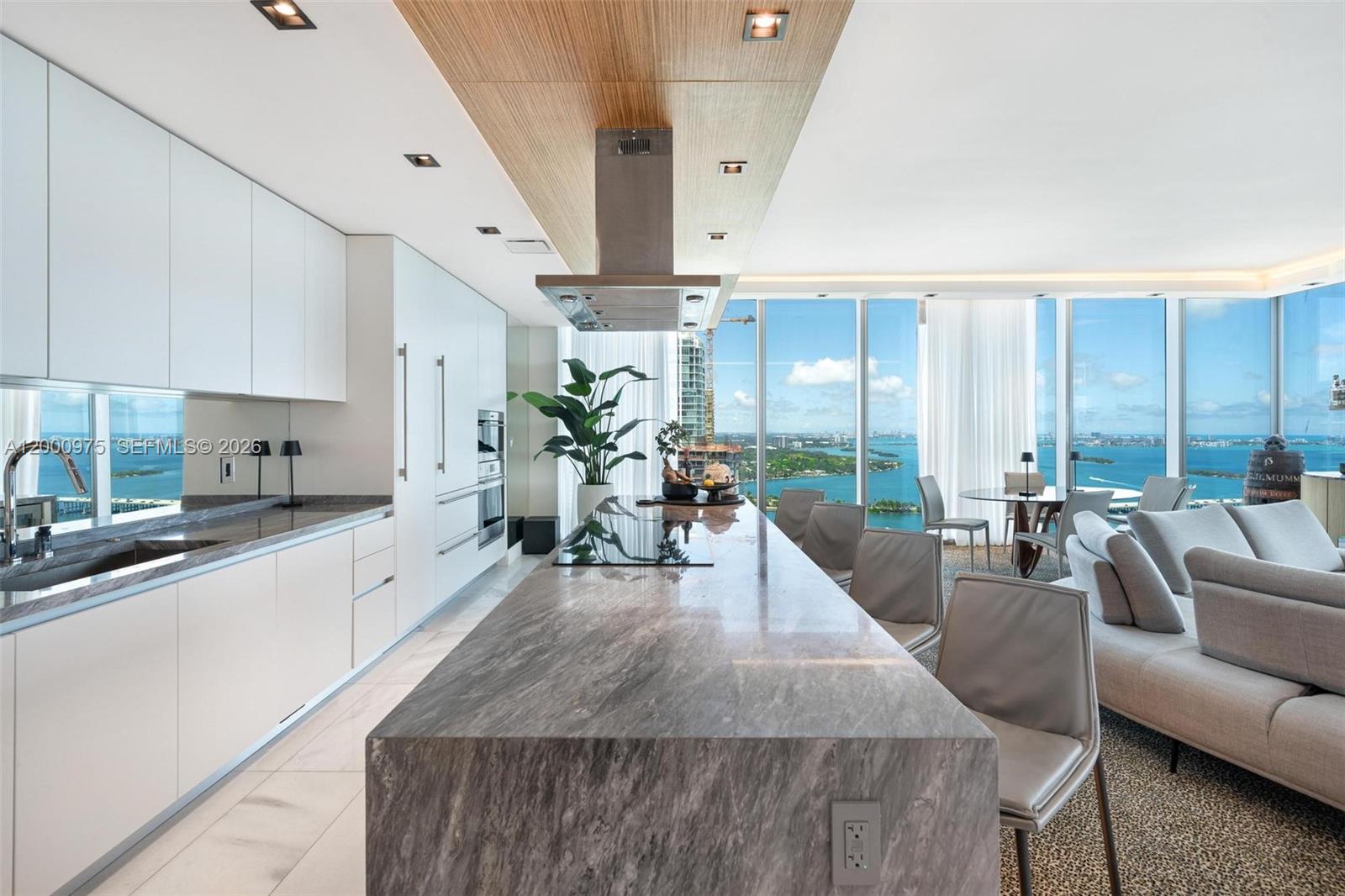 A modern kitchen with a stone island and white cabinetry overlooks a coastal city view — 700 NE 26th Ter # 3901, Miami FL 33137, MIAMI, FL