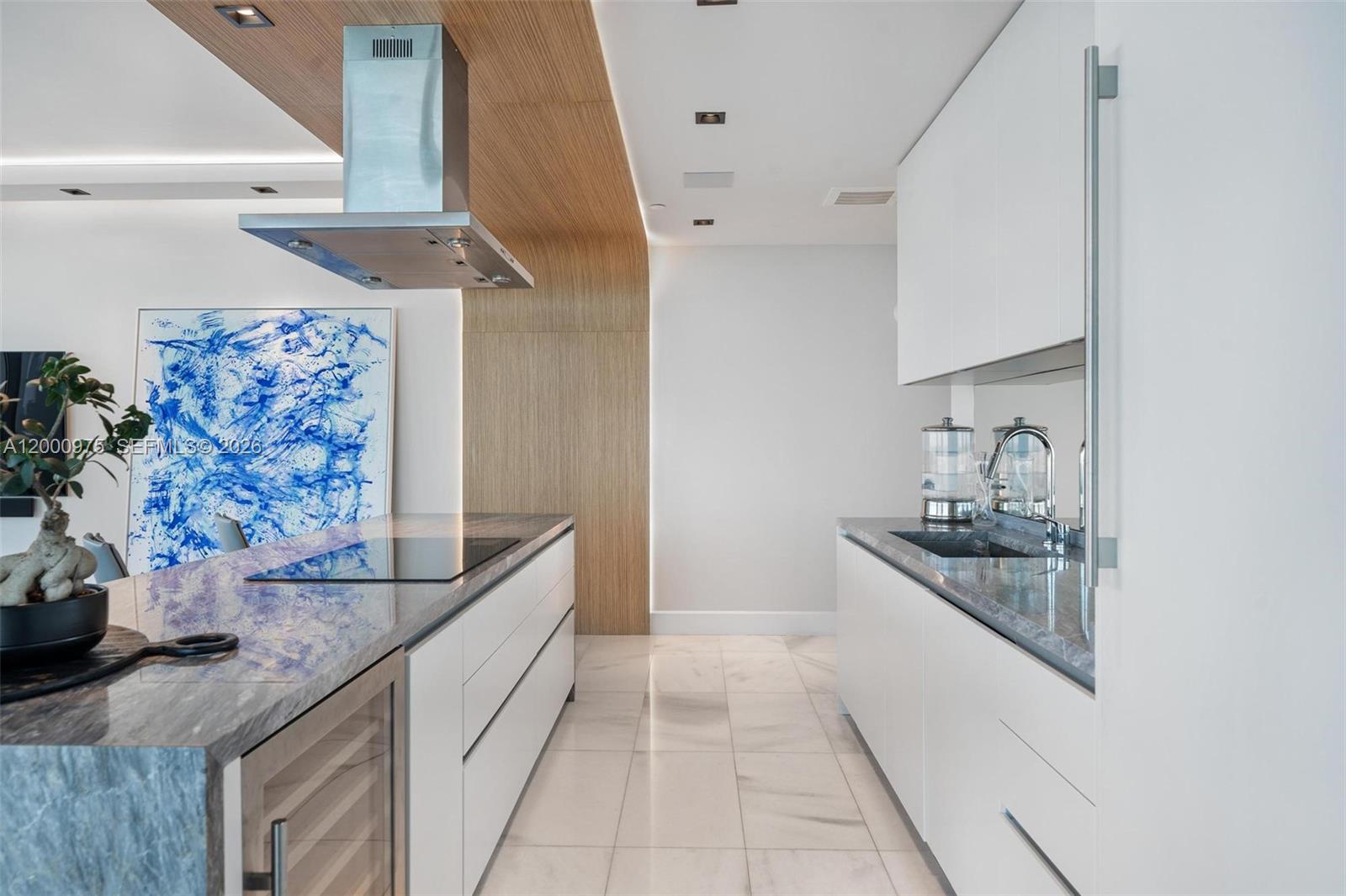 A modern kitchen features white cabinetry, marble countertops, and a wood-paneled ceiling accent — 700 NE 26th Ter # 3901, Miami FL 33137, MIAMI, FL