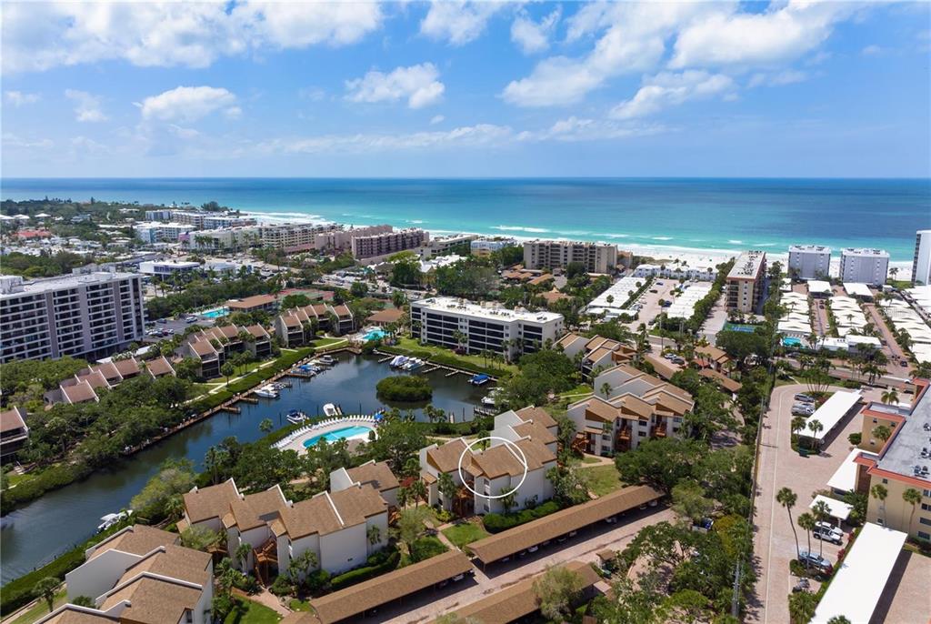 An aerial view shows a multi-story residential complex with a pool and boat slips — 1400 COVE II PLACE UNIT 631, SARASOTA, FL