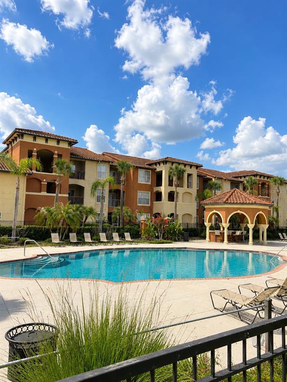 A swimming pool sits in front of a multi-story apartment building with a gazebo — 5542 METROWEST BOULEVARD UNIT 7-104, ORLANDO, FL