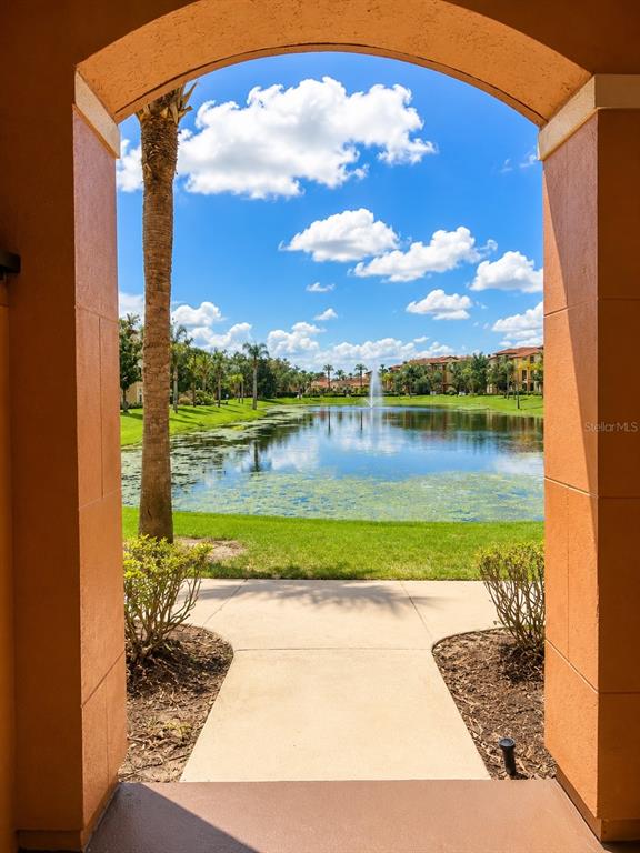 A view through an arched doorway looking out onto a pond with a fountain — 5542 METROWEST BOULEVARD UNIT 7-104, ORLANDO, FL