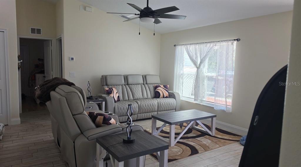 A living room features light gray reclining furniture, a coffee table, and a ceiling fan — 760 GRIFFIN AVENUE SW, PALM BAY, FL