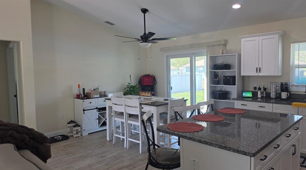 A kitchen and dining area with white cabinetry, granite countertops, and a ceiling fan — 760 GRIFFIN AVENUE SW, PALM BAY, FL