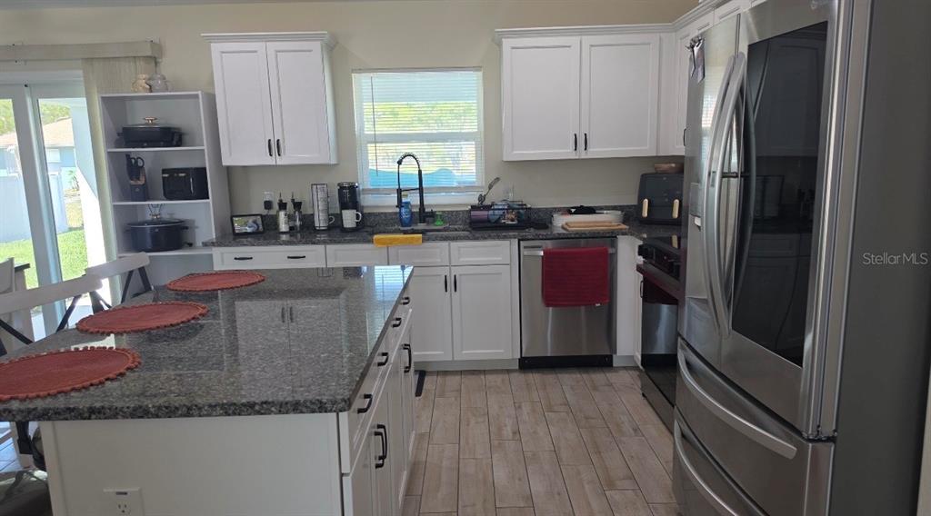 A kitchen features white cabinets, granite countertops, stainless steel appliances, and a central island — 760 GRIFFIN AVENUE SW, PALM BAY, FL