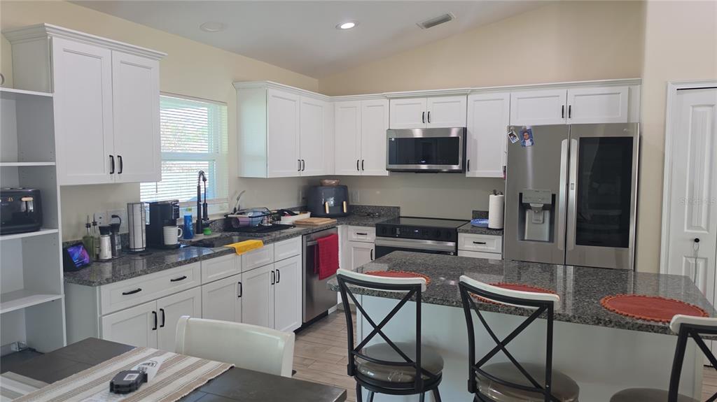 A kitchen features white cabinetry, granite countertops, stainless steel appliances, and a central island — 760 GRIFFIN AVENUE SW, PALM BAY, FL
