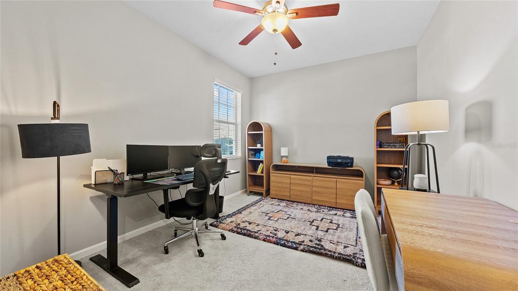 A living room features a gray sectional sofa, a patterned rug, and sliding glass doors — 891 JETWAY STREET, ORANGE CITY, FL
