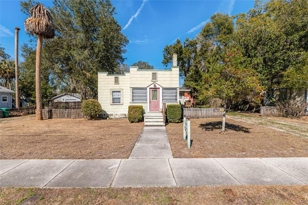 A single-story house with a flat roof and light-colored block exterior sits behind a lawn — 20707 PARK AVENUE, DUNNELLON, FL