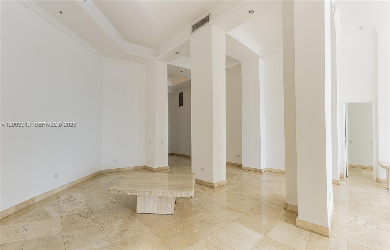 An empty room features white walls, large square floor tiles, and a stone coffee table — 808 Brickell Key Dr # 404, Miami FL 33131, MIAMI, FL