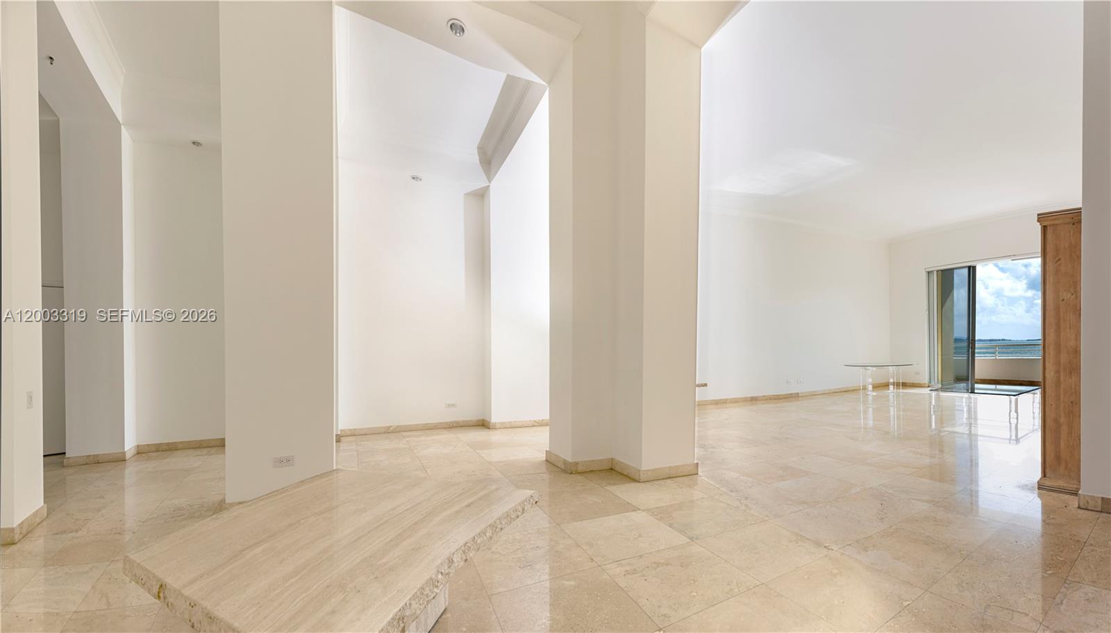 An open living area features white walls, beige tile flooring, large columns, and a balcony — 808 Brickell Key Dr # 404, Miami FL 33131, MIAMI, FL