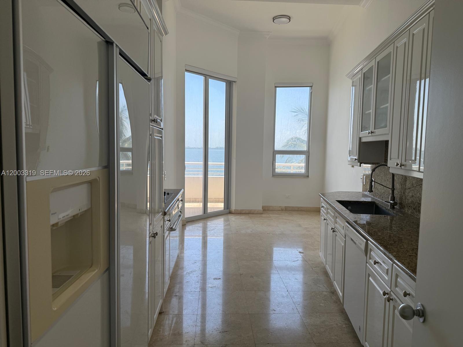 A galley kitchen features white cabinets, granite countertops, and a view of the ocean — 808 Brickell Key Dr # 404, Miami FL 33131, MIAMI, FL