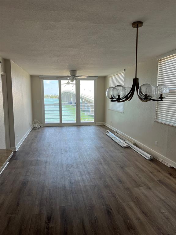 An empty room with wood-look flooring, a modern chandelier, and a view of a bridge — 5701 BAHIA DEL MAR CIRCLE UNIT 508, ST PETERSBURG, FL