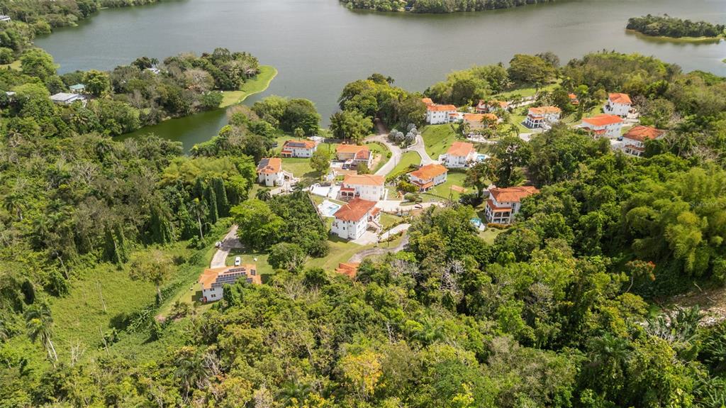 An aerial view shows several houses with red roofs nestled in a lush, wooded landscape — Carretera PR-175 KM. 4.0k ESMERALD LAKE PLANTATION, TRUJILLO ALTO, PR