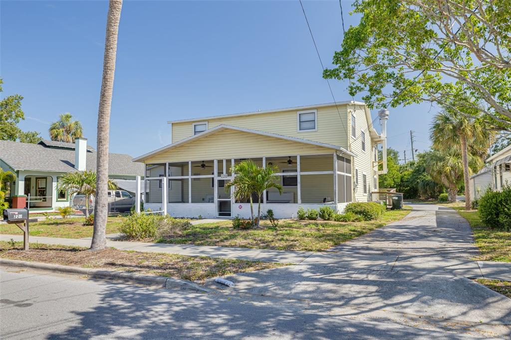 A two-story yellow house with a large screened-in front porch and a paved driveway — 220 SCOTLAND STREET, DUNEDIN, FL