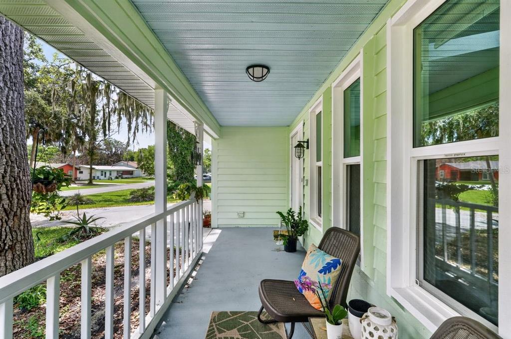A covered porch features light green siding, a blue ceiling, and a white railing — 2012 MANGO TREE DRIVE, EDGEWATER, FL