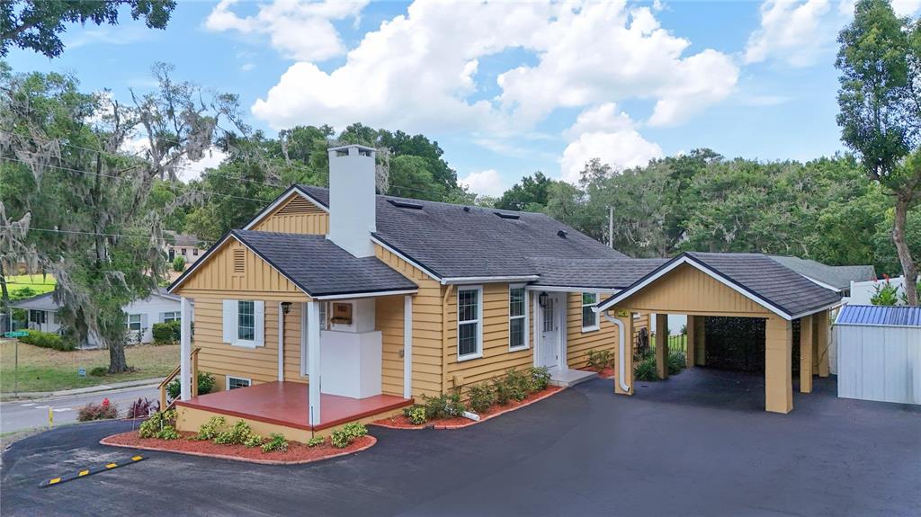 A yellow house with a covered carport, a front porch, and a white chimney — 102 N CLAYTON STREET, MOUNT DORA, FL