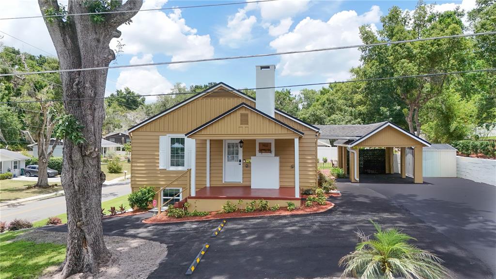 A yellow house with a front porch, a chimney, and a carport over a driveway — 102 N CLAYTON STREET, MOUNT DORA, FL
