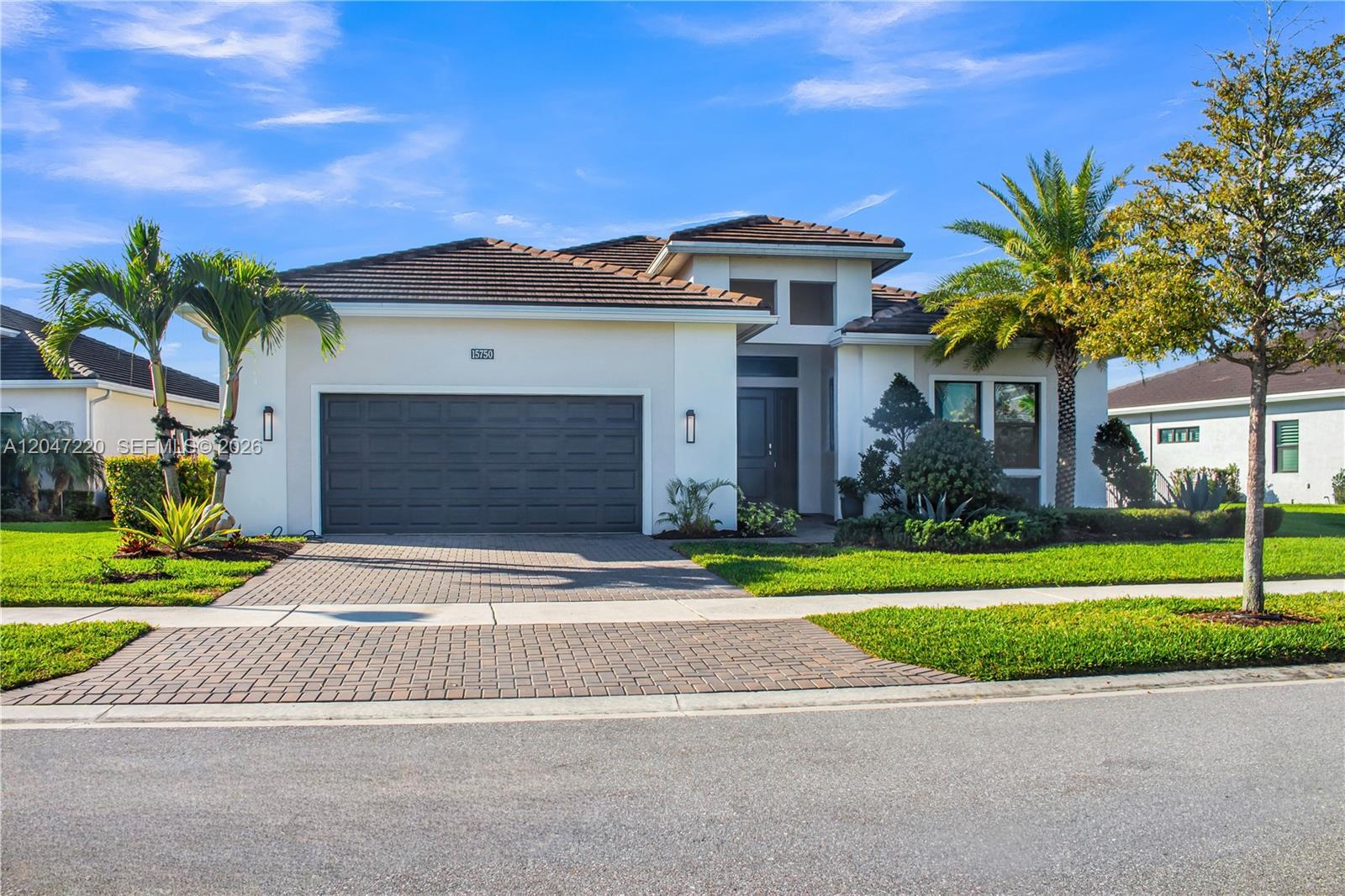 A single-story house with a paved driveway, a two-car garage, and palm trees — 15750 Longboat Key Dr, Westlake FL 33470, WESTLAKE, FL